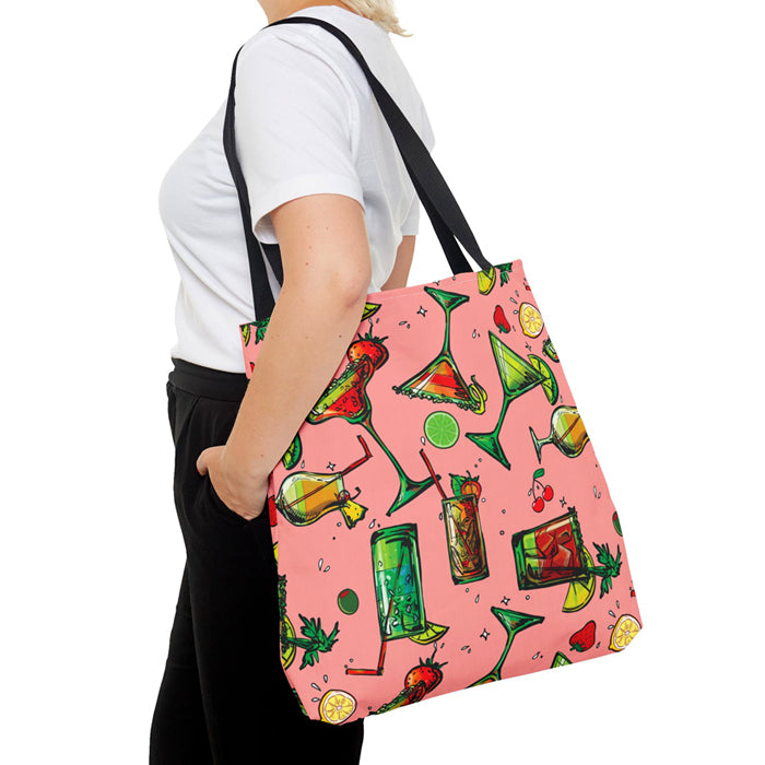 Person holding a pink tote bag with colorful drink pattern on a white background