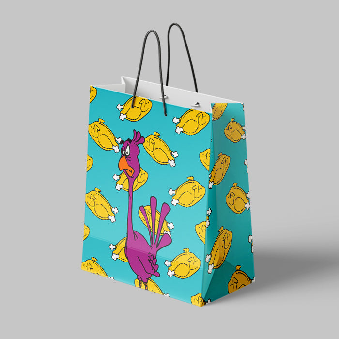 A square paper shopping bag with black twisted handles, featuring a bright turquoise background printed with a repeating pattern of yellow roasted chicken pieces and a large purple cartoon chicken on the front, shown on a neutral gray background.