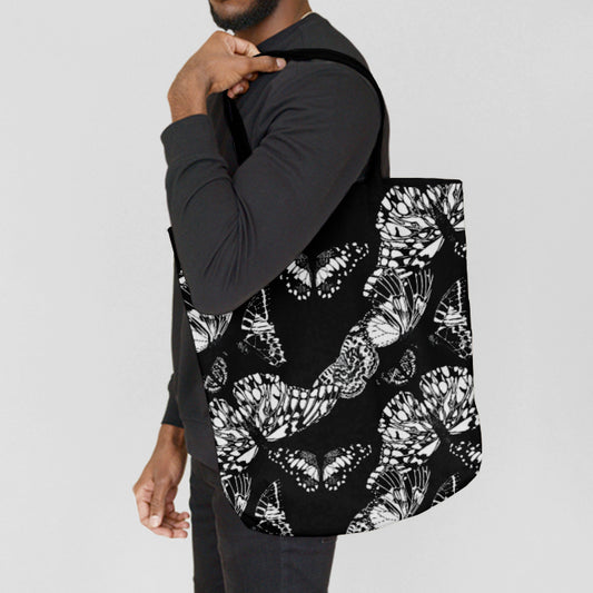 Person carrying a black tote bag with white butterfly pattern on a light gray background