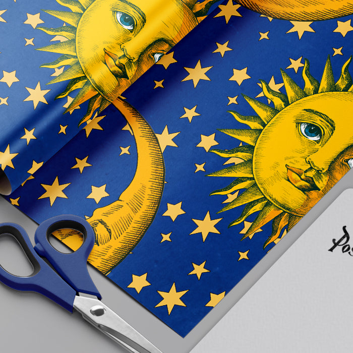 Decorative paper with sun and moon design and stars, scissors on a blue background