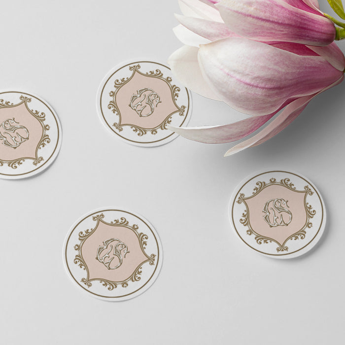 Round decorative stickers with a floral design on a light surface with a pink flower.
