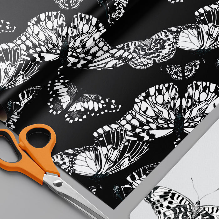 Butterfly patterned wrapping paper with scissors on a black background