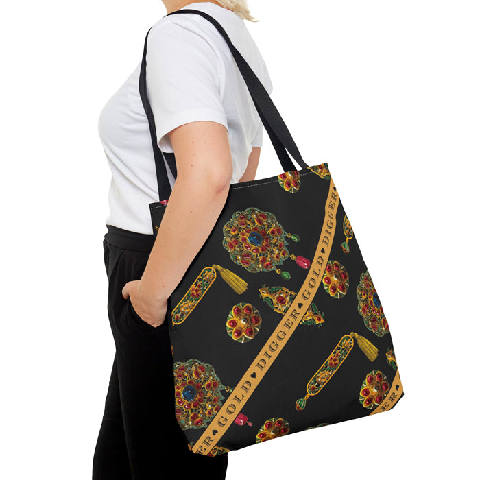 Person holding a black tote bag with colorful jewel pattern and 'Digger Gold' text.