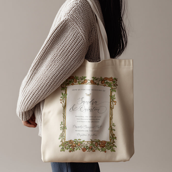 Tote bag with wedding invitation design held by a person wearing a beige sweater.