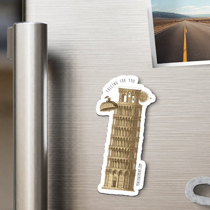 A die-cut magnet featuring the leaning tower of Pisa shown attached to a stainless steel refrigerator door next to a photo print.