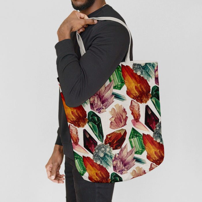 Person holding a tote bag with colorful crystal design on a plain background