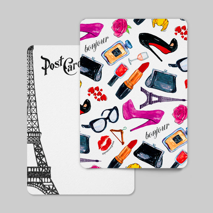 Postcard with Paris-themed design featuring Eiffel Tower, lipstick, high heels, and other fashion items on a gray background.