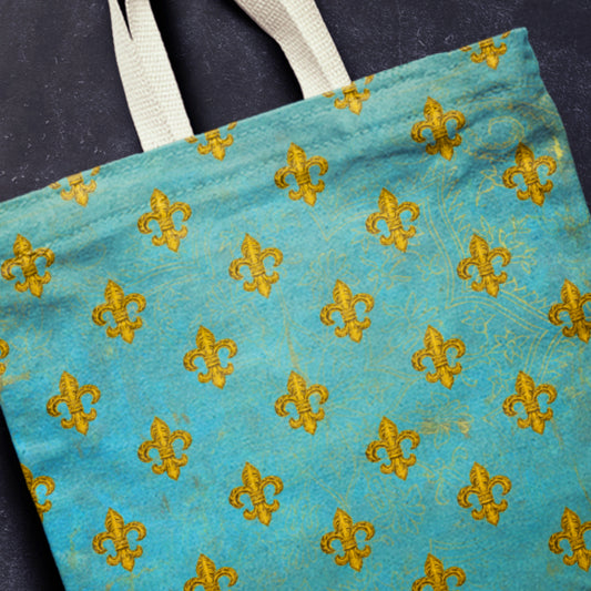 Blue tote bag with yellow fleur-de-lis pattern on a dark background
